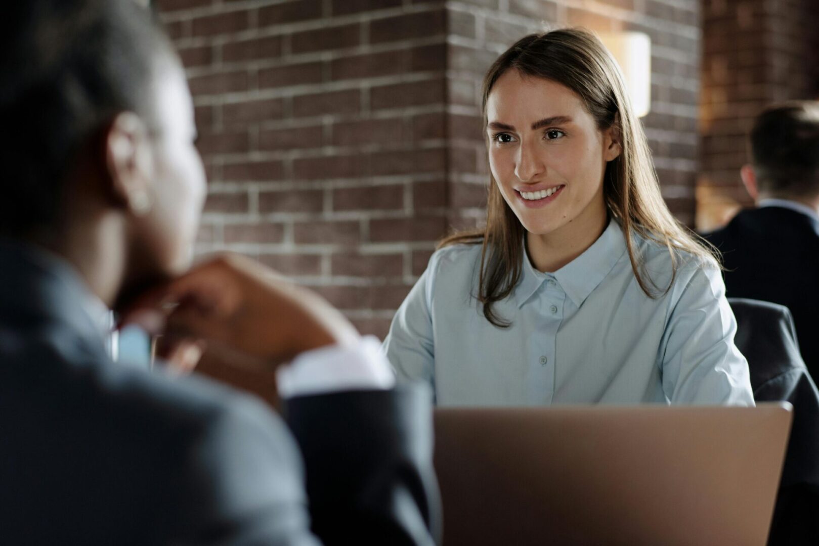 A woman converses with a man in a professional office setting, both engaged in discussion.