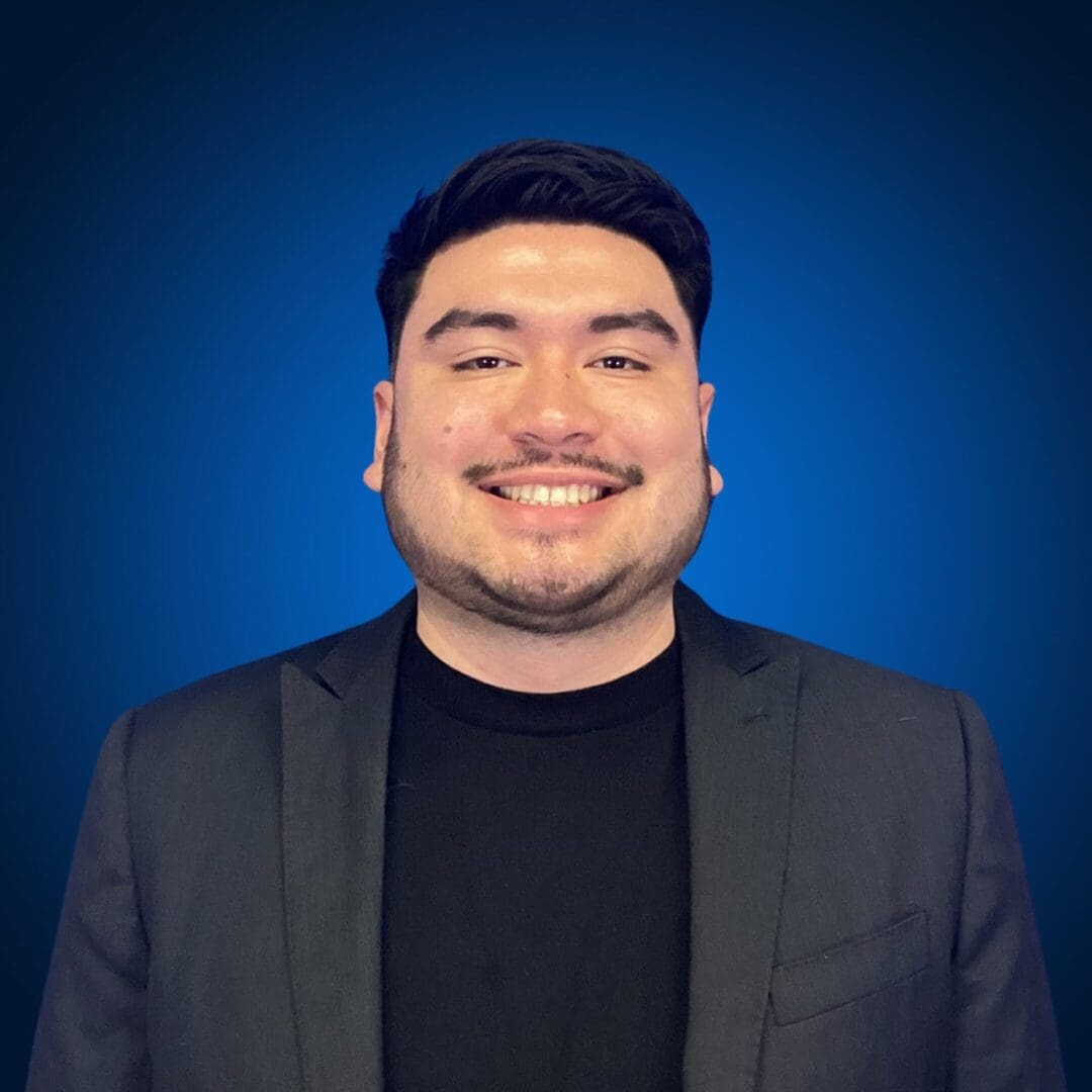 Smiling person in a suit, blue background.