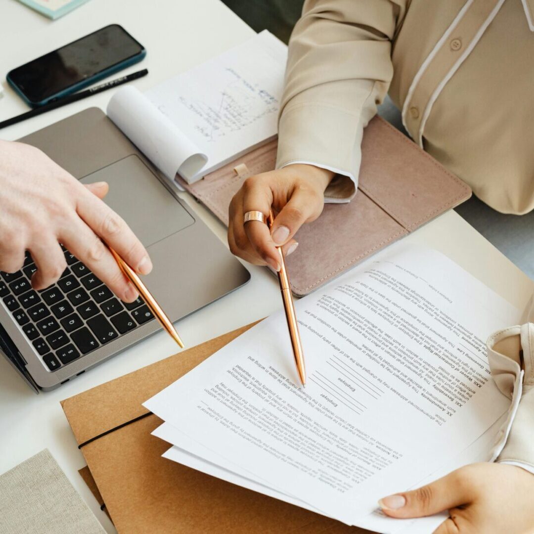 Two individuals collaborating on paperwork at a desk, focused on their tasks in a professional setting