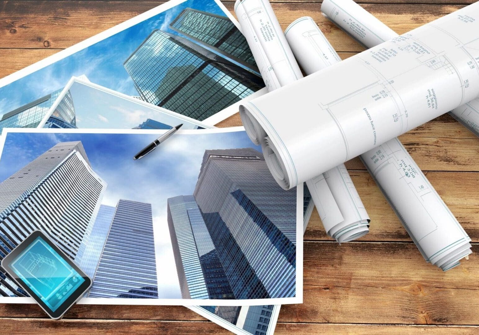 Architectural blueprints and skyscraper photos on table