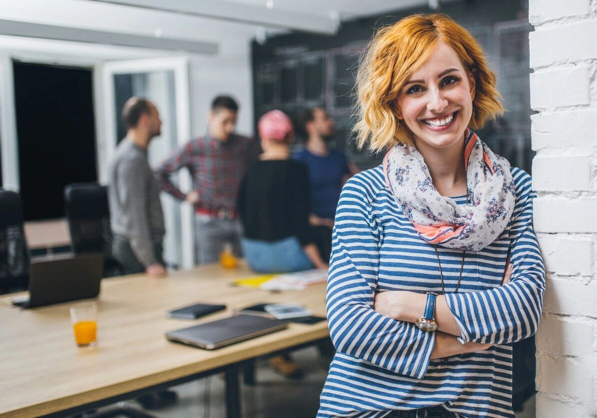 A woman stands confidently in front of a diverse group of people, engaging them with her presence.