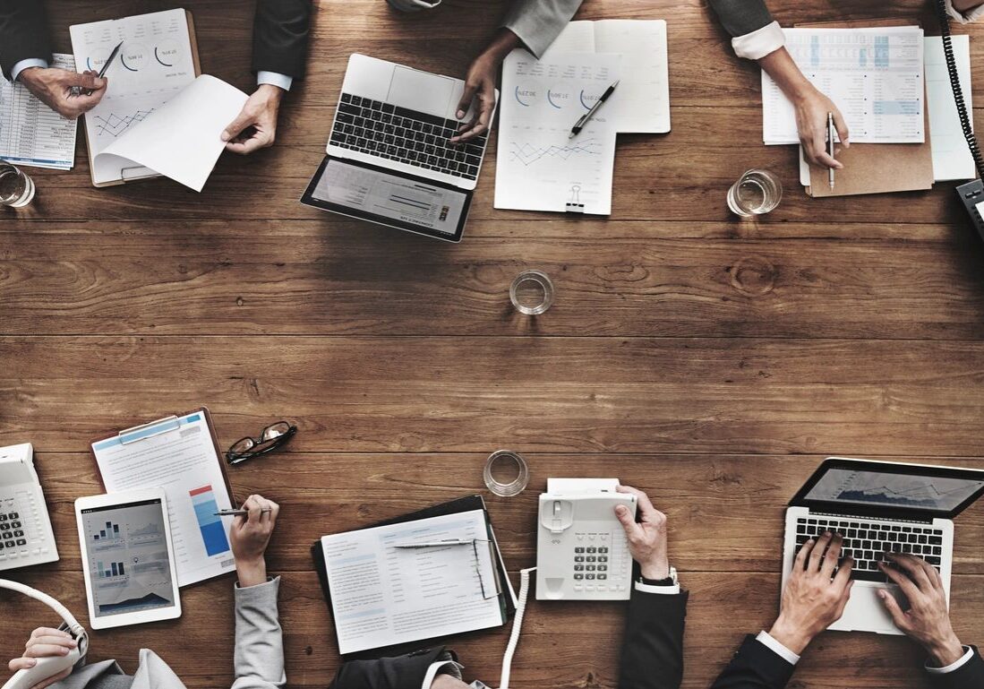 Business professionals collaborating at a table, using laptops and reviewing documents.